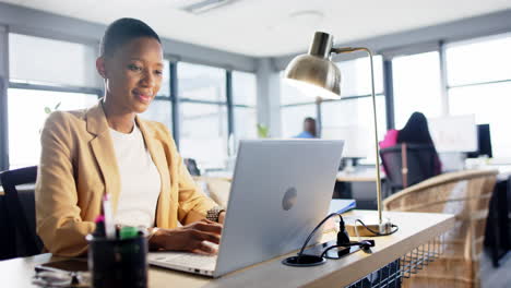 Retrato-De-Una-Sonriente-Mujer-De-Negocios-Afroamericana-Usando-Una-Computadora-Portátil-En-La-Oficina,-Cámara-Lenta,-Espacio-Para-Copiar