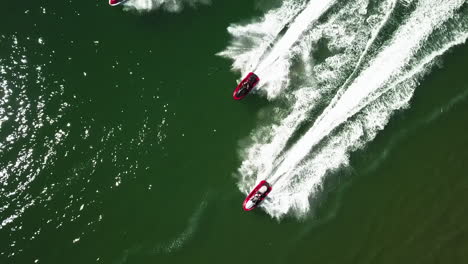 bird's eye view of a group of red, black and white water scooters in green sea