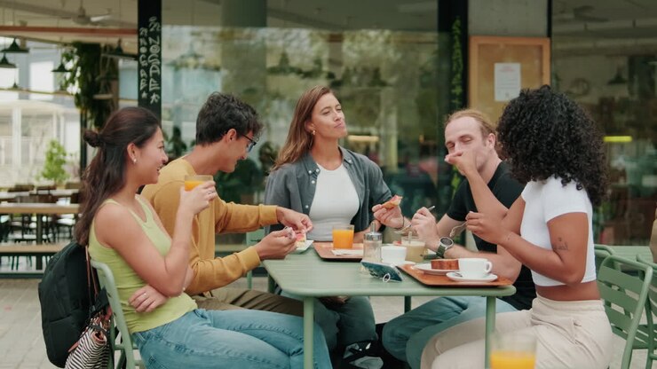 International joyful students drink soft drinks at lunch, eating, talking and