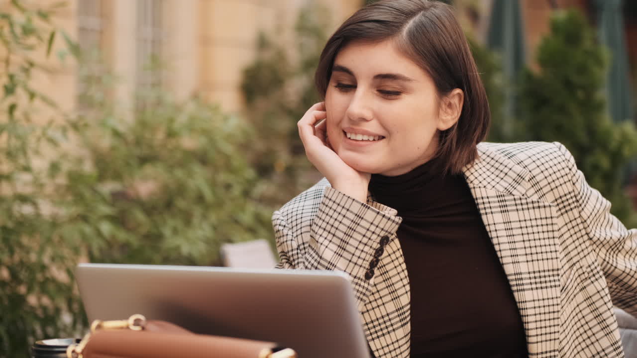 Businesswoman working on laptop in cafe outdoor.