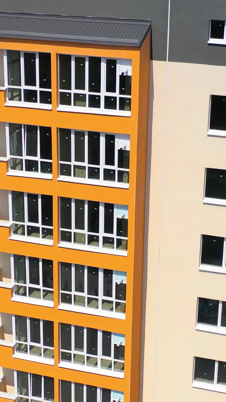 Facade of newly built skyscraper. Modern building with bright walls in the city. High raised building with large windows and balconies. Front view. Vertical video