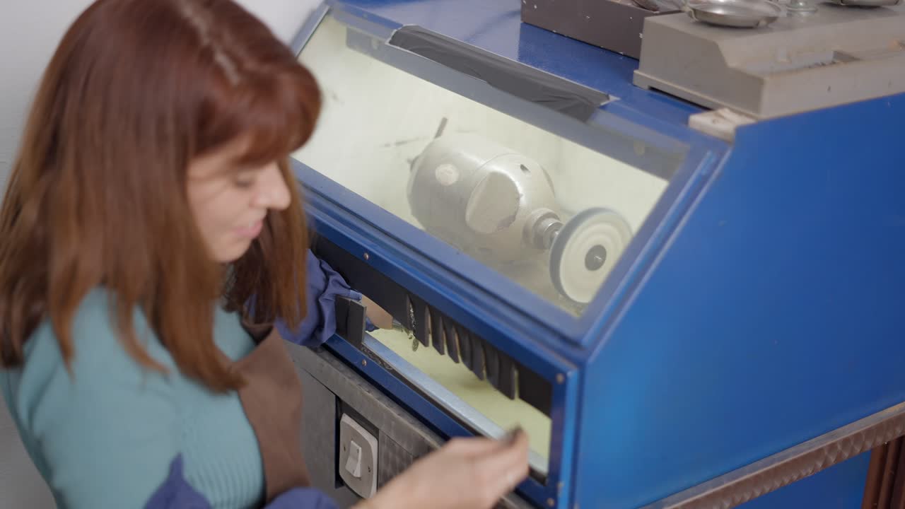 Woman working on jewelry repair with polishing machine