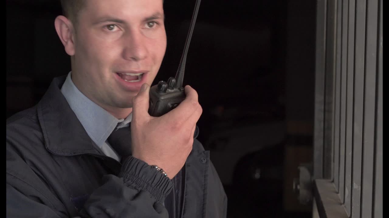Latino man security guard of a building, is in the parking lot giving an information on the radio