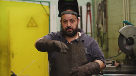 Caucasian-male-factory-worker-at-a-factory-standing-in-a-workshop,-looking-to-the-camera