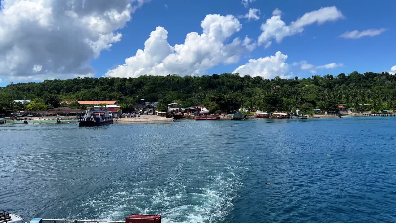 A ferry unloads at a tropical village port surrounded by lush forest and vibrant blue waters—ideal for travel, transport, and lifestyle themes