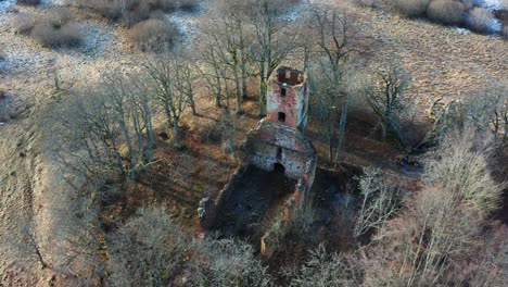 drone view above abandoned church bell tower and wall remains, bare tree around