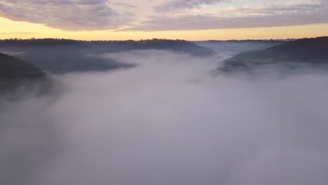 australian valley covered in thick fog with mountain tops and colorful clouds during sunrise in new south wales near sydney