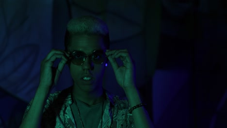 vista de cerca de un joven afroamericano con estilo poniéndose las gafas y divirtiéndose en una fiesta por la noche