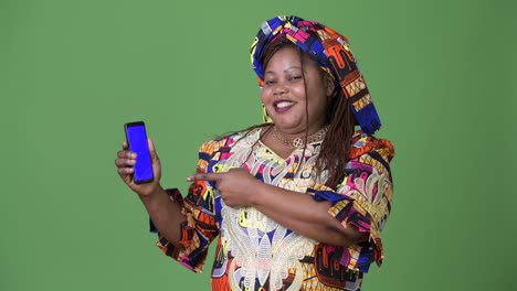 overweight beautiful african woman wearing traditional clothing against green background