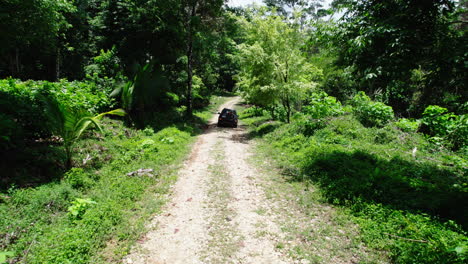 Vista-Posterior-Del-Automóvil-Conduciendo-Por-Un-Camino-Forestal-Lleno-De-Baches-En-Una-Zona-Tropical