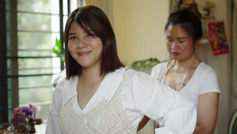 woman trying on a macrame vest with assistance from a tailor