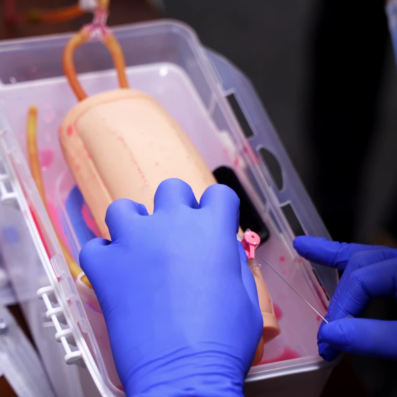 Catheter insertion learning. Students in sterile gloves study to put a catheter on a dummy hand. Medical training. Close-up.