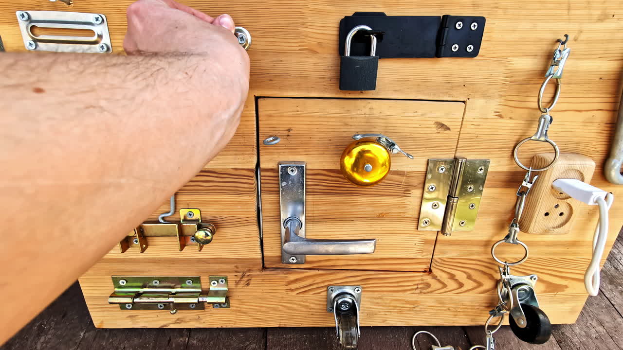 POV of hand struggle to close chain door guard on sensory board