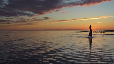 Einsame-Frau,-Die-Bei-Sonnenuntergang-Im-Seichten-Meer-Spazieren-Geht-Und-Sich-Nach-Einem-Geliebten-Menschen-Sehnt