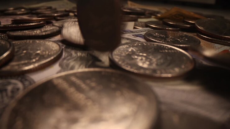 Monete d'argento che cadono su banconote da un dollaro, primo piano, filmato 4K al rallentatore.