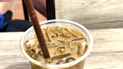 hand stirring iced coffee with a straw