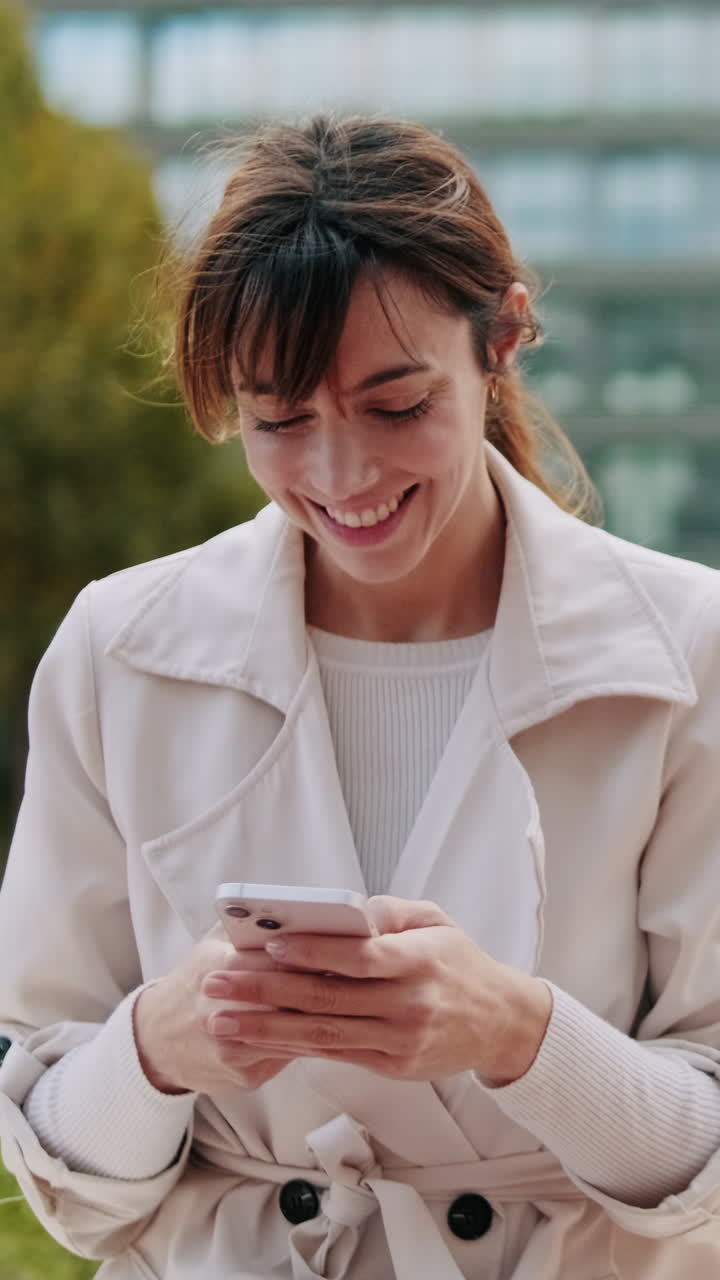Giovane donna sorridente che usa lo smartphone all'aperto