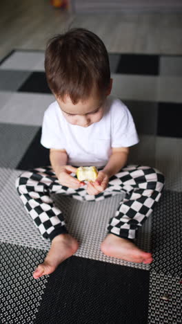 small child have organic nutrition. eating apple cute little boy on a floor. vertical video.