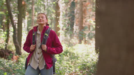 woman closing eyes enjoying peace as group of female friends on holiday hike through woods together