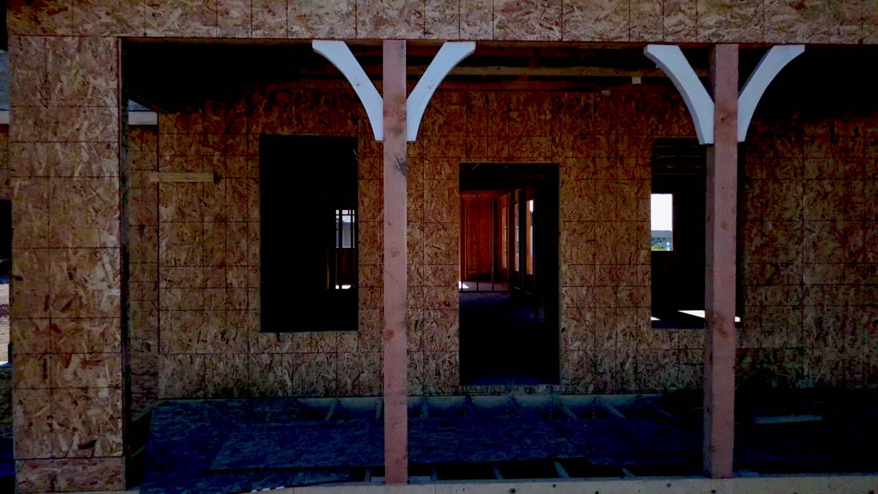 벽과 지붕이 거의 없는 새로 지어진 집에서 뒤로 물러나는 드론 샷