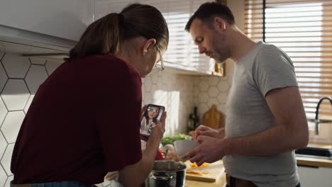 chica adolescente caucásica y su padre haciendo una videollamada con su madre mientras cocinan