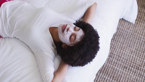 mujer afroamericana con máscara facial acostada en la cama