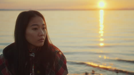 young asian woman standing by lake at sunset, watching scenic nature