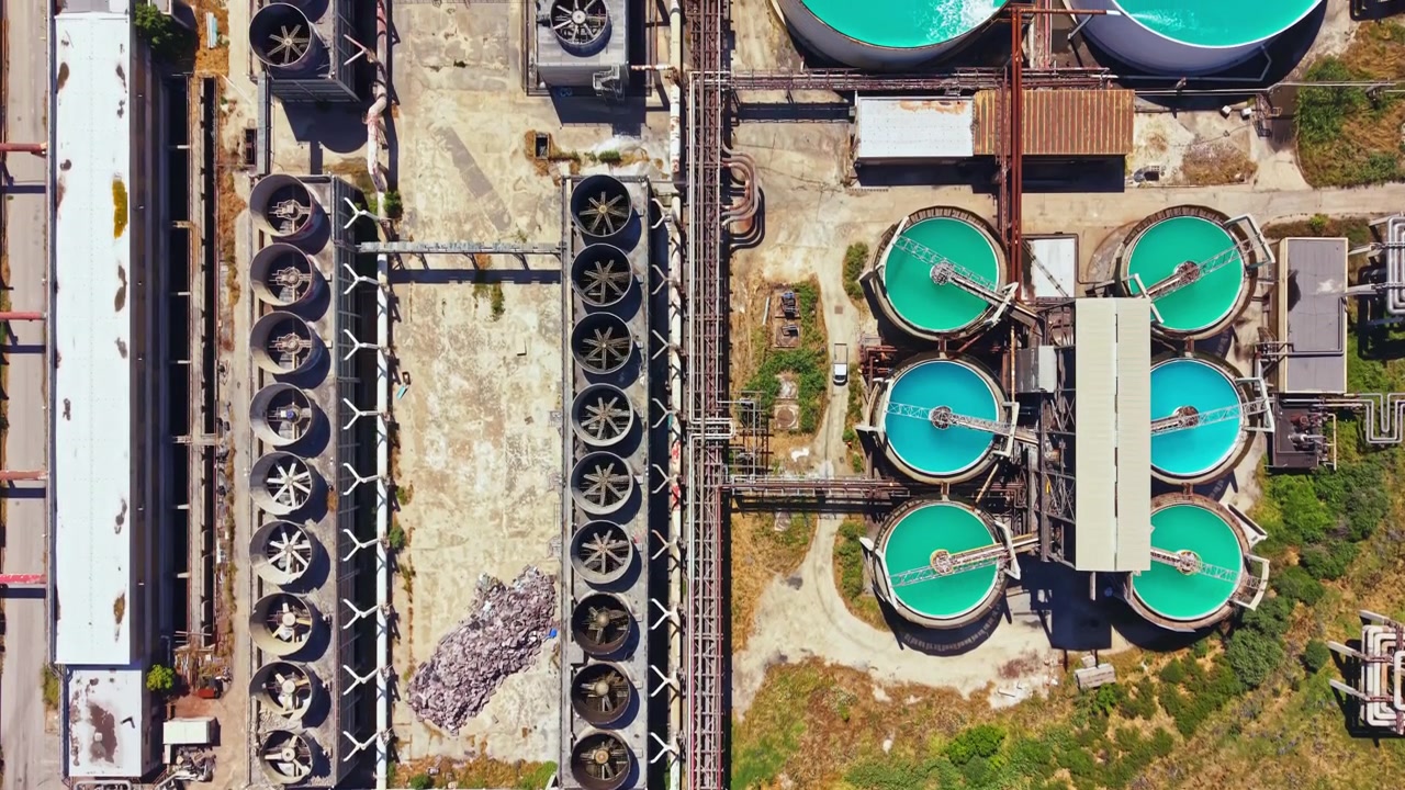Birds eye view of a water treatment facility with large tanks and industrial structures seen from above during daylight hours