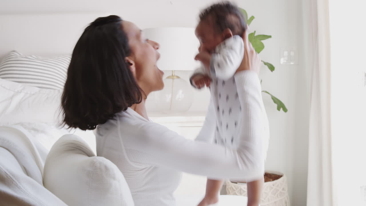 Millennial African American mother lifting her baby and kissing his tummy
