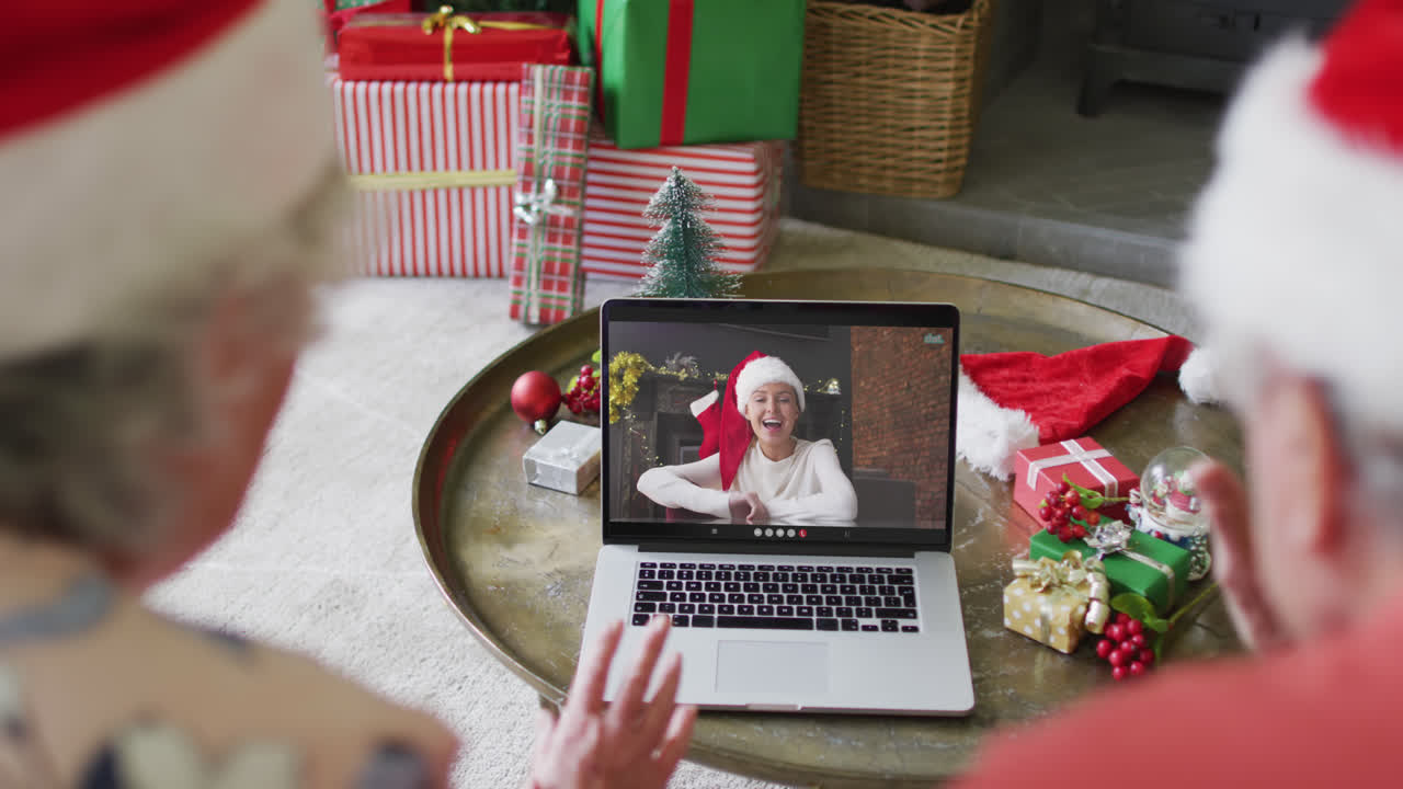 pareja caucásica de alto nivel usando un portátil para una videollamada de navidad con una mujer feliz en la pantalla