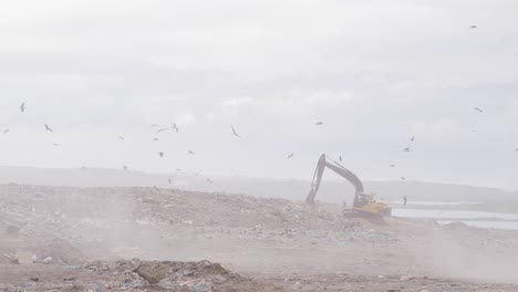 digger clearing rubbish piled on a landfill full of trash