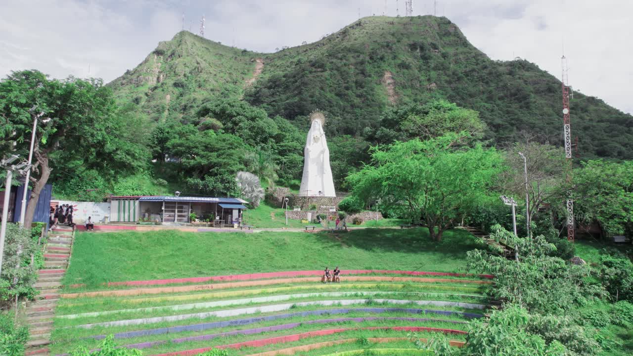 Zoom in aerial view of Virgin Mary statue and surrounding hills in Yopal, Guatemala, with lush greenery and mountain backdrop