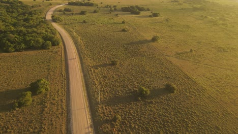 Vista-Aérea-De-La-Motocicleta-En-La-Carretera-Rural-Durante-La-Puesta-De-Sol