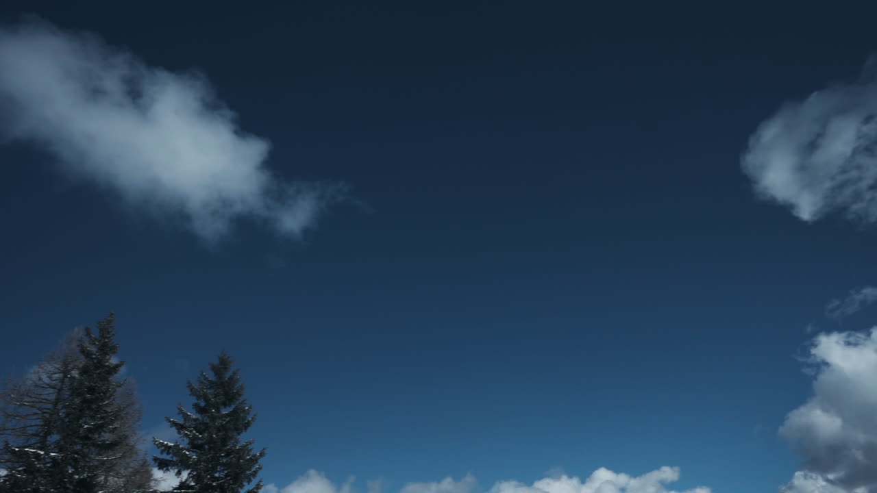 Actionbillede af en snowboarder, der flyver gennem luften, mens han laver et trick i bjergene. Optagelserne fanger bevægelse, højde, vinterforhold og dynamisk udendørs sportsenergi.