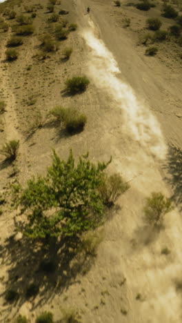un sendero curvo de polvo sigue a un motociclista en colinas arbustos fpv. un motociclista viaja hasta el pico de la montaña durante las carreras de motocross. un majestuoso paisaje aéreo