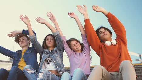 a group of teenage friends of two girls and two boys raise their hands and dance to the compass