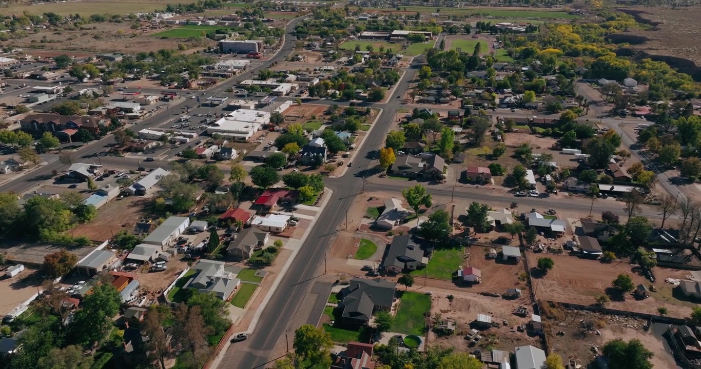Low aerial overview above Kanab Utah homes and streets surrounded by red desert landscape, drone background for real estate