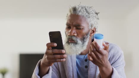 senior man using smartphone while holding empty medication container