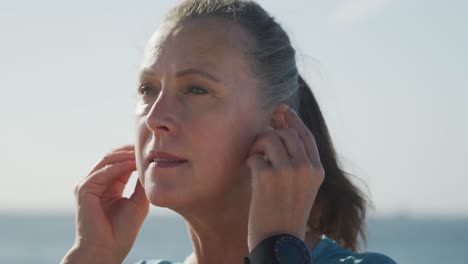 primer plano de una mujer mayor usando auriculares inalámbricos