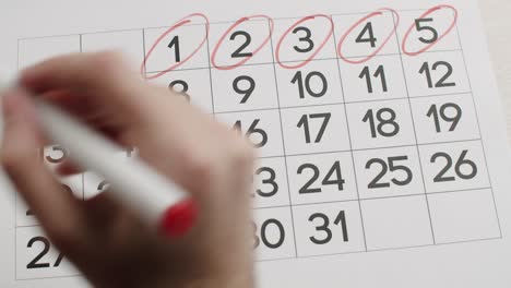 la mano del hombre escriba el día 6,7,8,9,10,11,12 en el calendario usando un bolígrafo rojo.