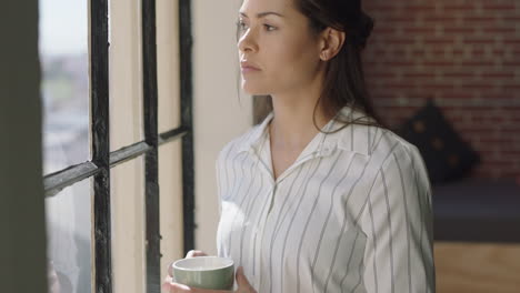 hermosa mujer hispana usando un teléfono inteligente bebiendo café en casa disfrutando de una mañana relajada navegando por mensajes mirando por la ventana pensando contemplativamente