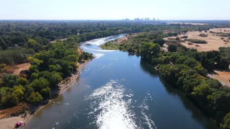 Una-Excelente-Toma-Aérea-De-Personas-Que-Se-Adentran-En-El-Río-Americano-En-Sacramento,-California.