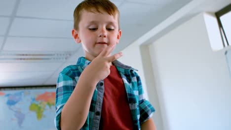 caucasian schoolboy sitting over desk and counting with his finger in classroom 4k