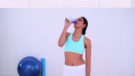 mujer en forma caminando y bebiendo de una botella deportiva