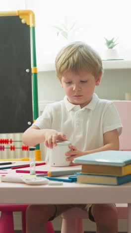 un niño pequeño examina los humidificadores de mesa sentado en el escritorio en la sala de juegos en cámara lenta. una estudiante corta figuras de papel de colores pasando tiempo con su hermano menor