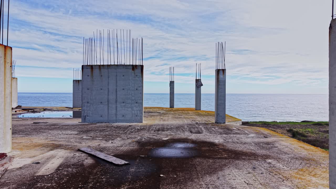 Construction site overlooking the ocean with concrete pillars and rebar