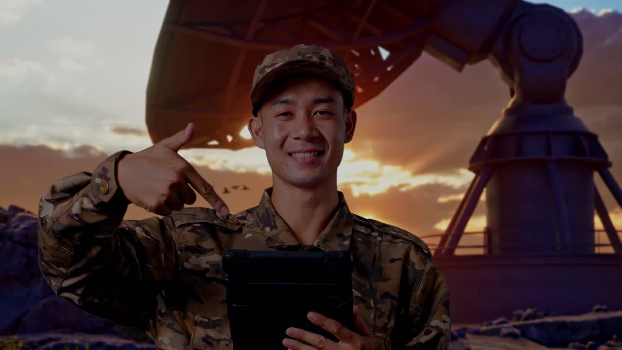 Close Up Of Asian Man Soldier Smiling And Pointing To A Tablet In His Hand While Standing With Satellite Dish