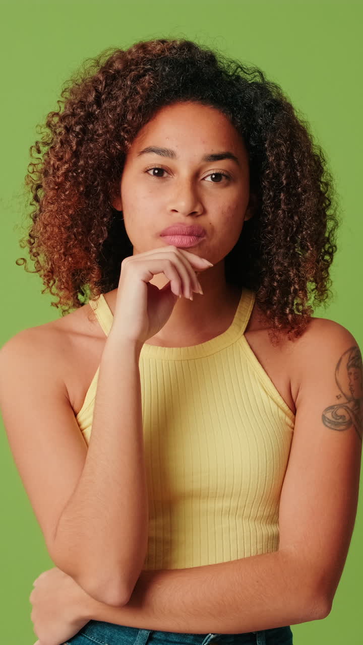 Thoughtful Young Woman Pondering and Looking at Camera on Green Screen