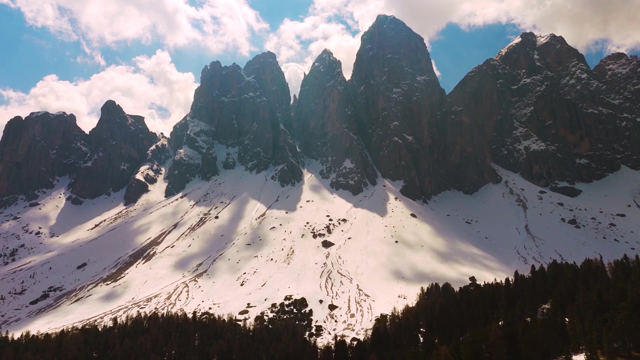 Odle bjergets snedækkede tinder, der rejser sig fra fyrreskoven i Puez-Geisler Naturpark. Italienske Dolomitter