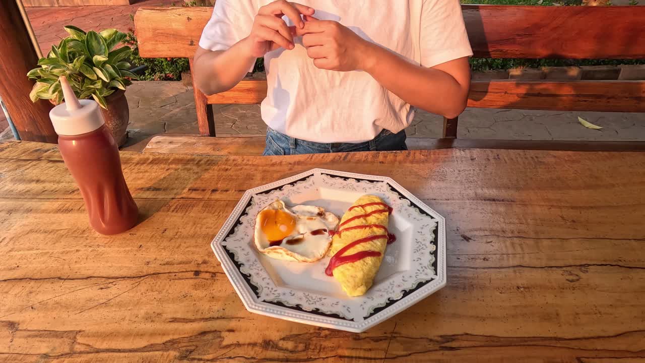 persona aderezando el desayuno con ketchup en una mañana soleada